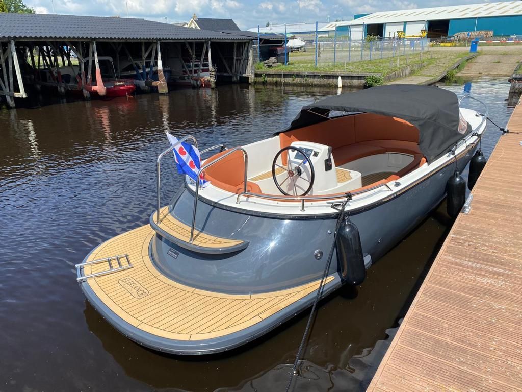 Een boot ligt aangemeerd aan een steiger naast een watermassa.