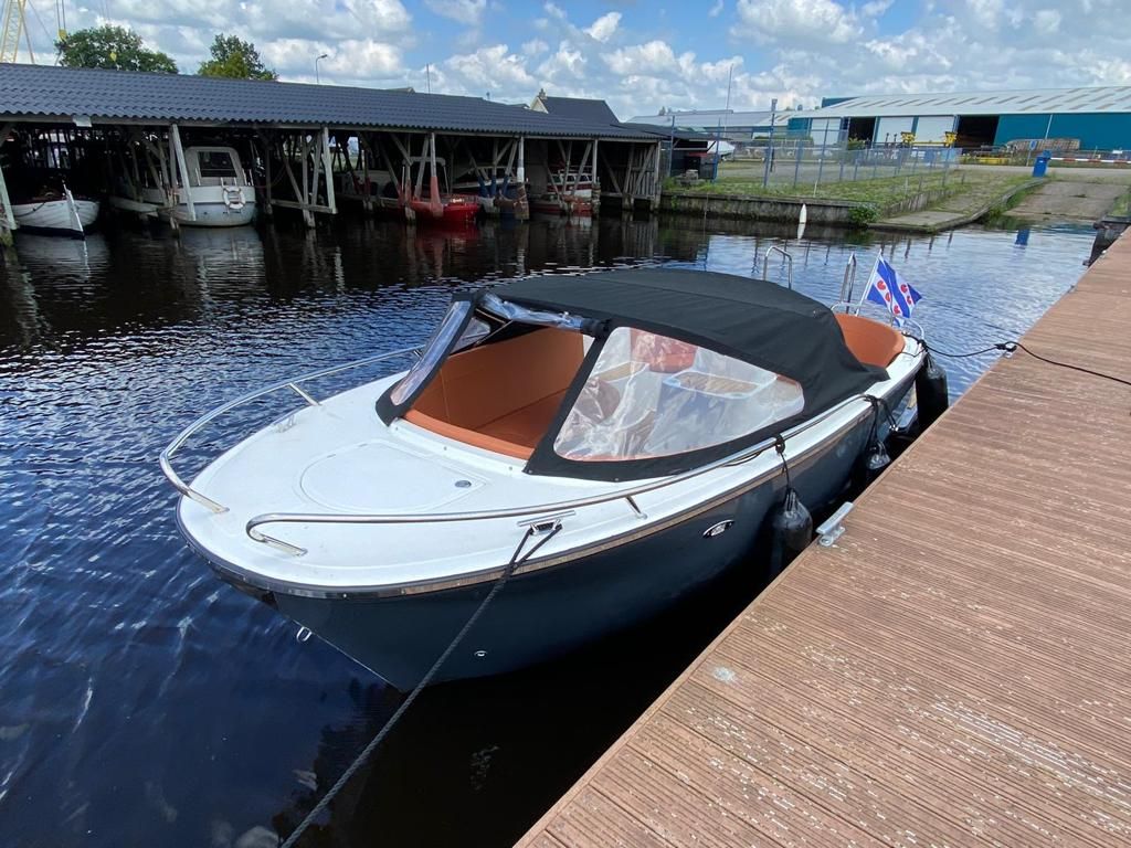Een boot ligt aangemeerd aan een steiger naast een watermassa.
