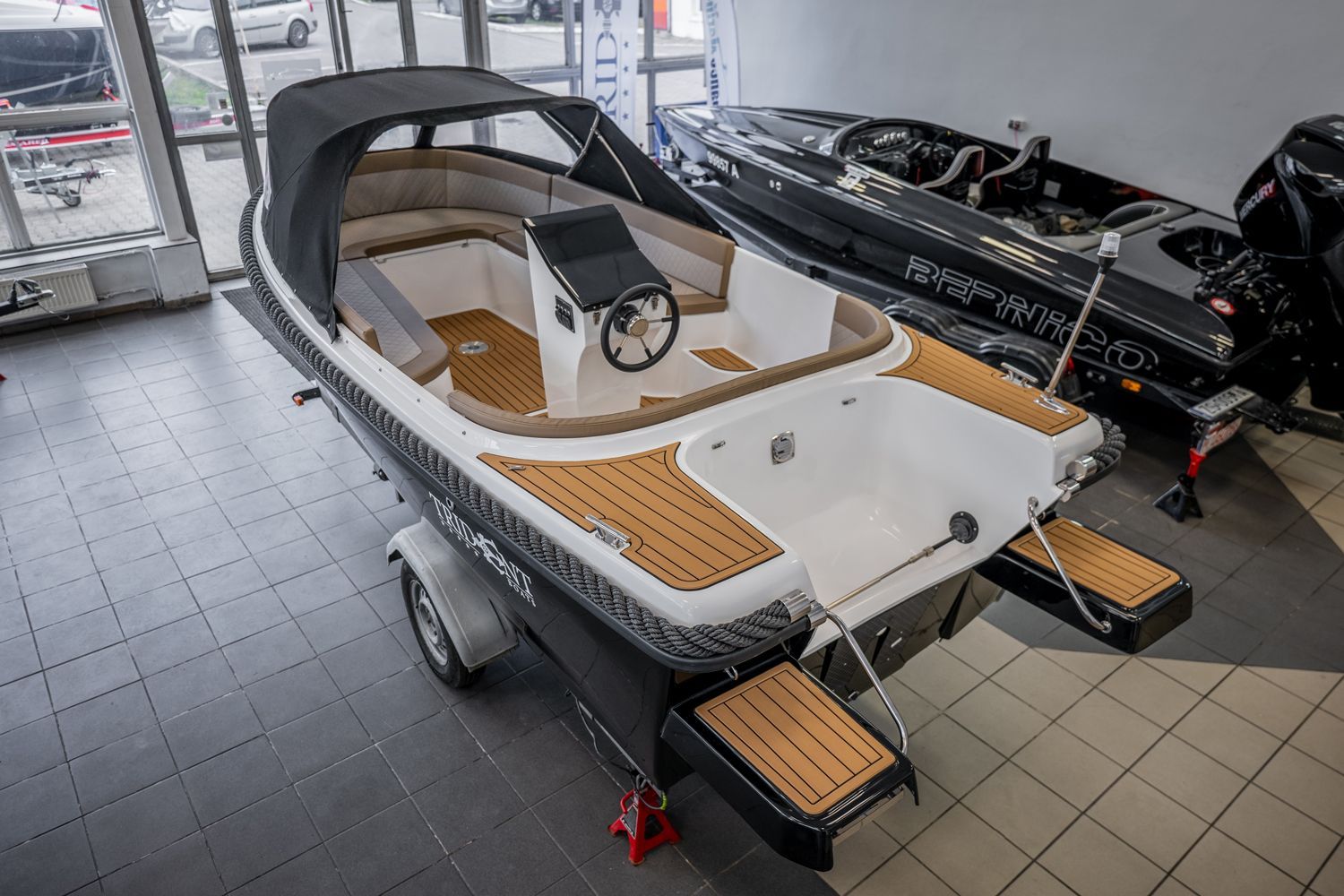 Een kleine boot staat op een trailer in een showroom.