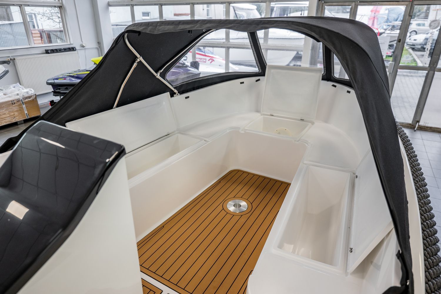 De binnenkant van een boot met een houten dek en een zwarte kap.