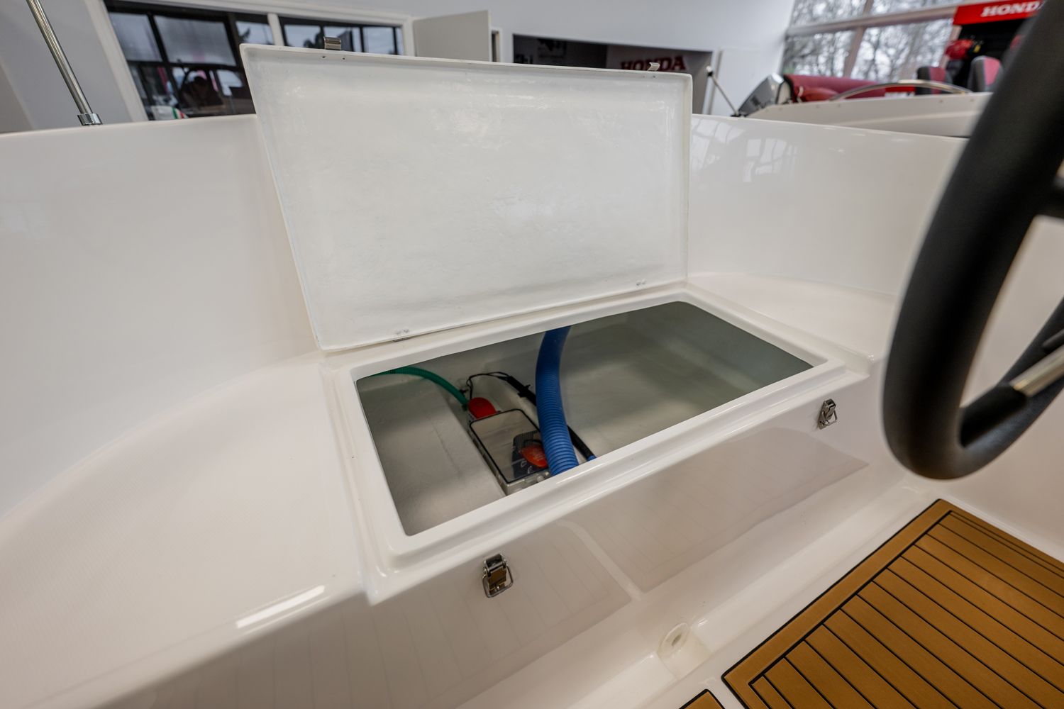 Een witte boot met het deksel open en een stuurwiel.