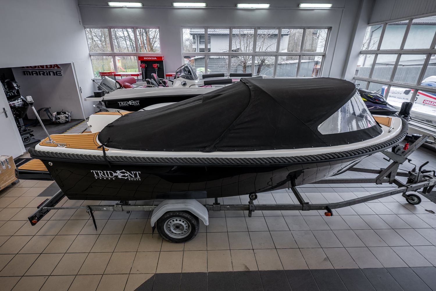 Een boot staat op een trailer in een showroom.
