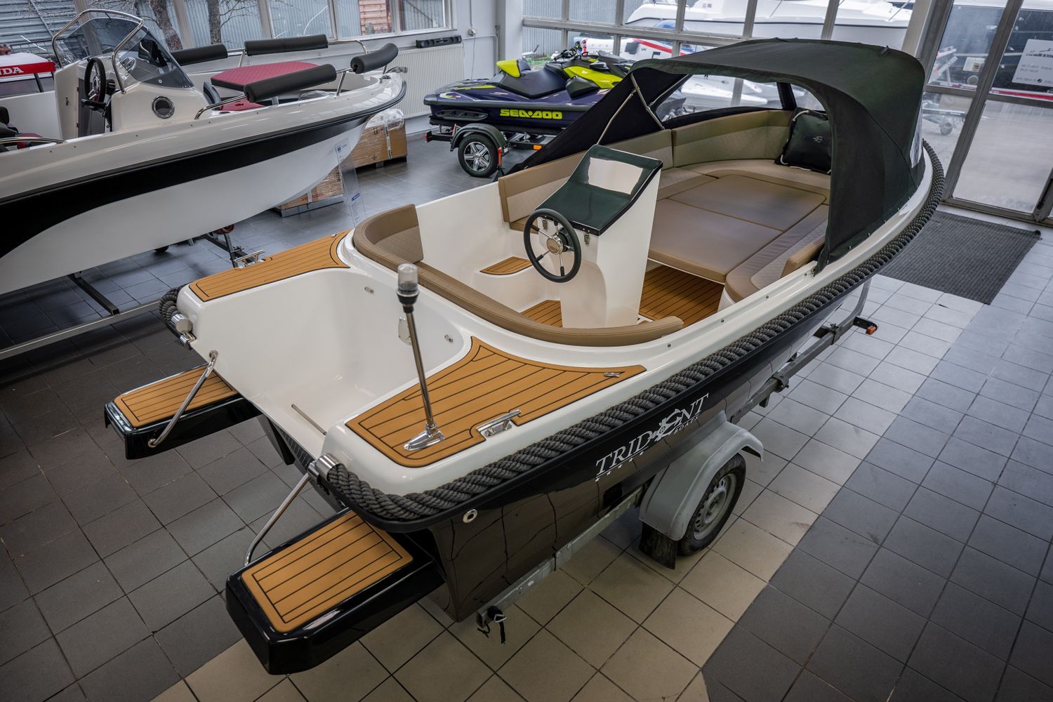 Een kleine boot staat op een trailer in een showroom.