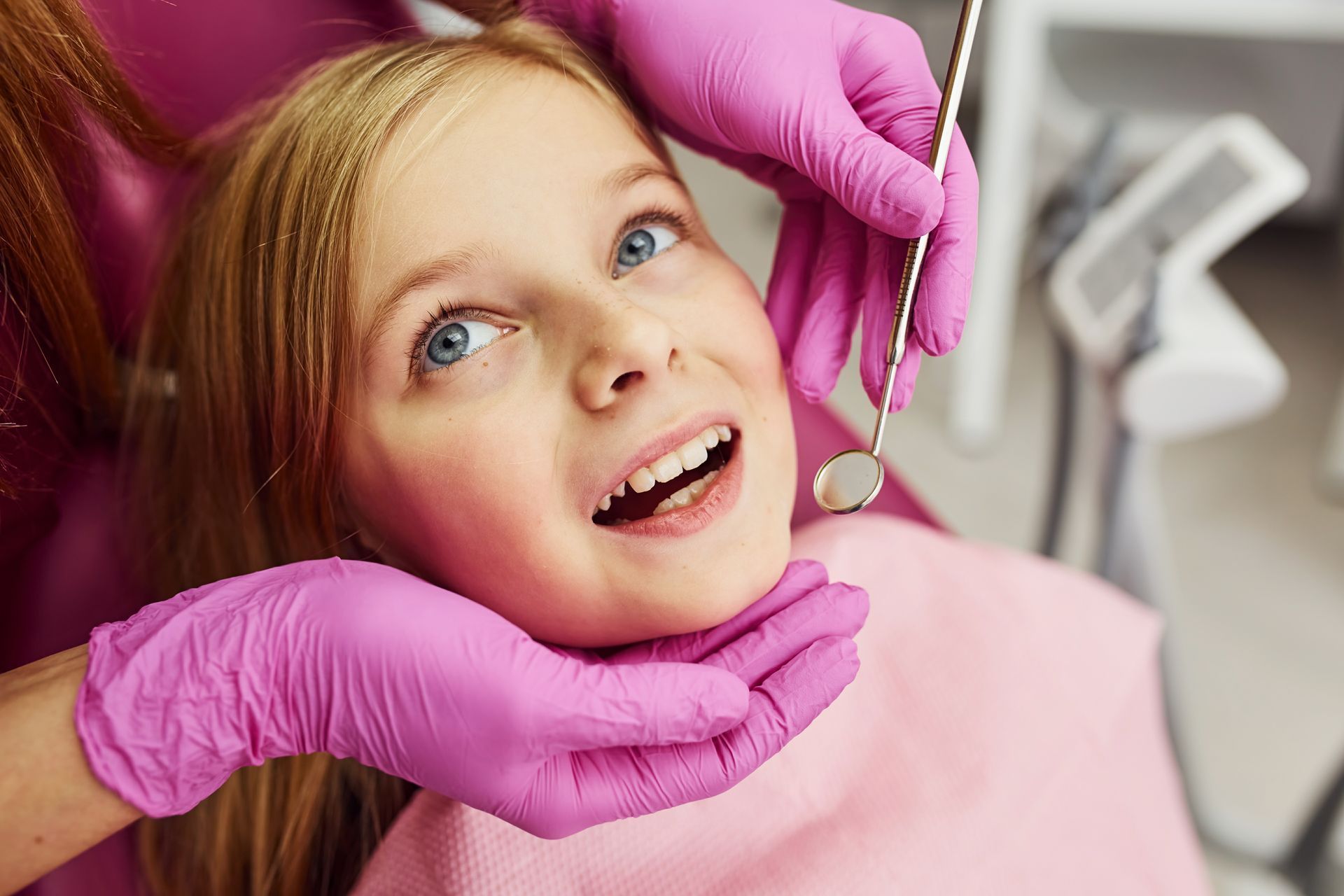 A little girl is getting her teeth examined by a dentist.