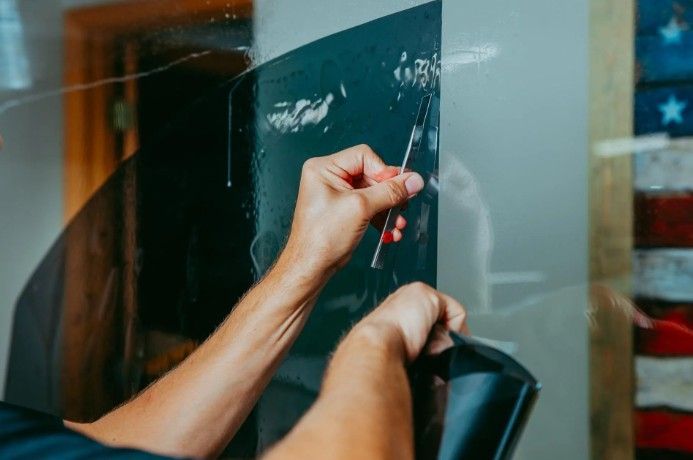 Hands writing on a glass board with white marker in a classroom or office setting