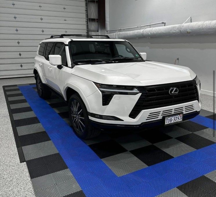 White Lexus SUV parked indoors on a checkered floor with blue stripes