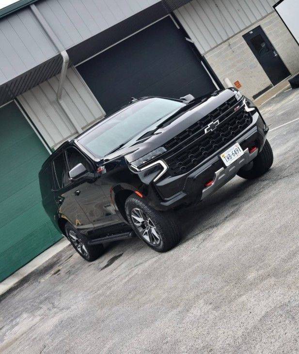 Black SUV parked at a tilted angle in an industrial lot beside a warehouse