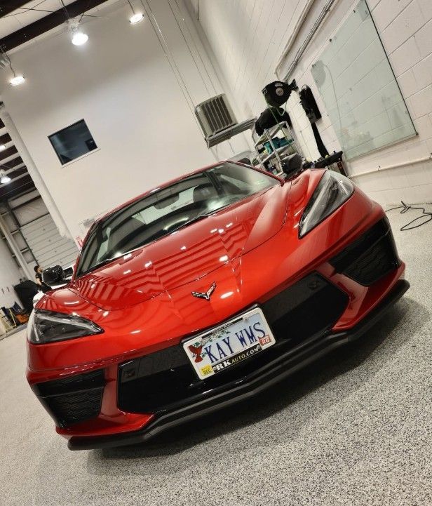 Red Chevrolet Corvette in a garage, front view with bright red paint and custom license plate.