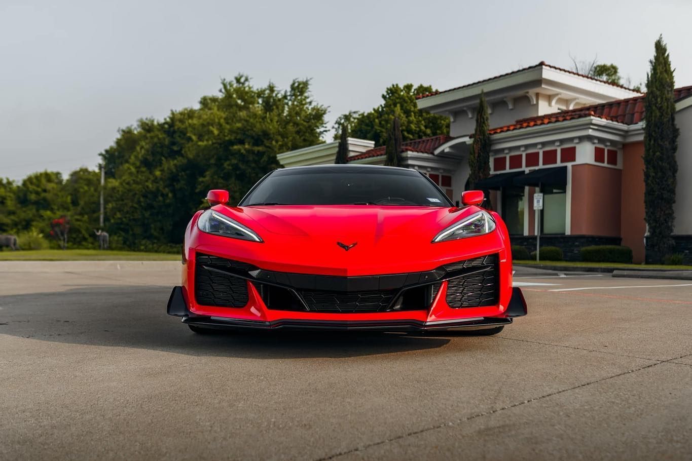 A red corvette is parked in front of a building.