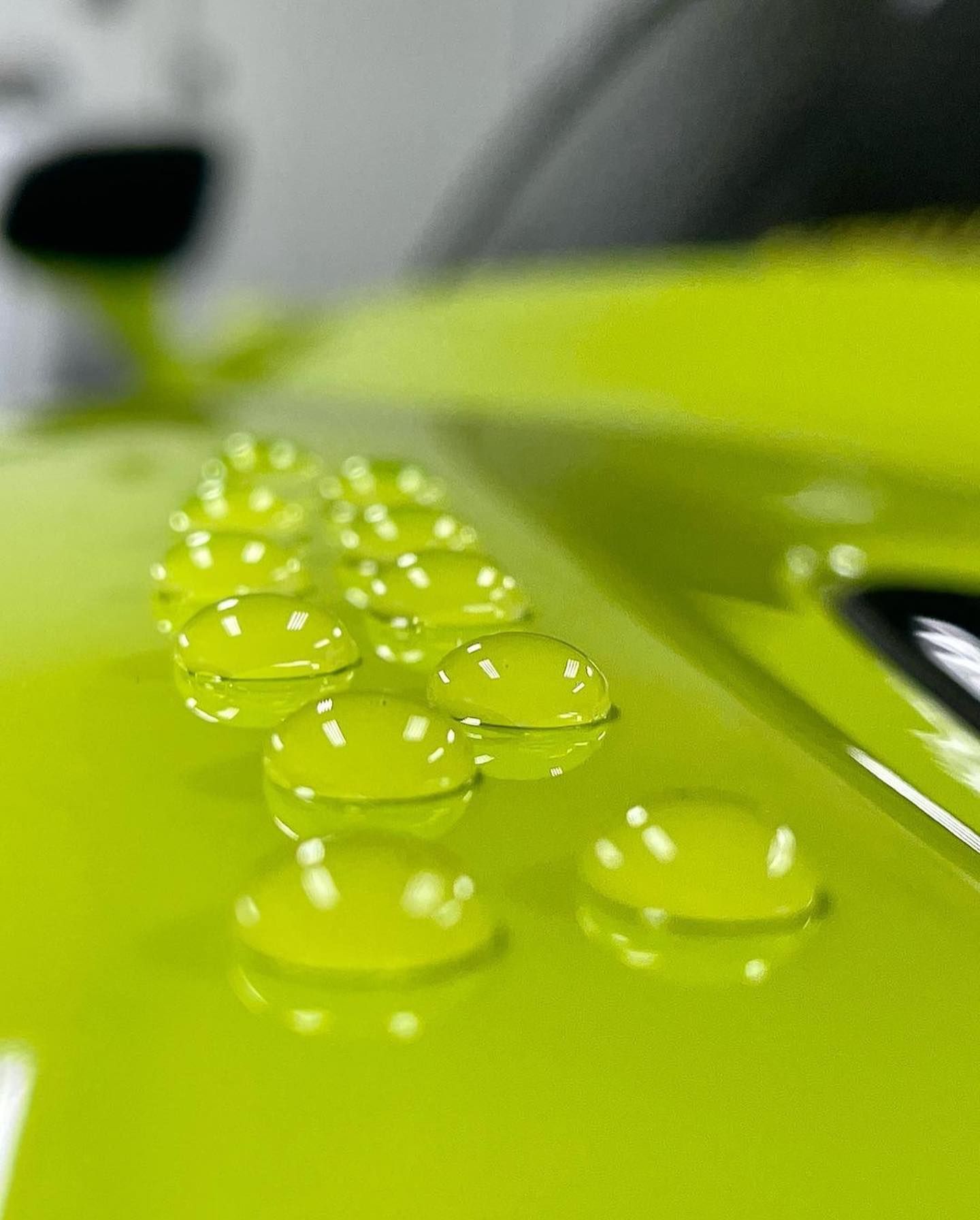 A close up of a green car with water drops on it.
