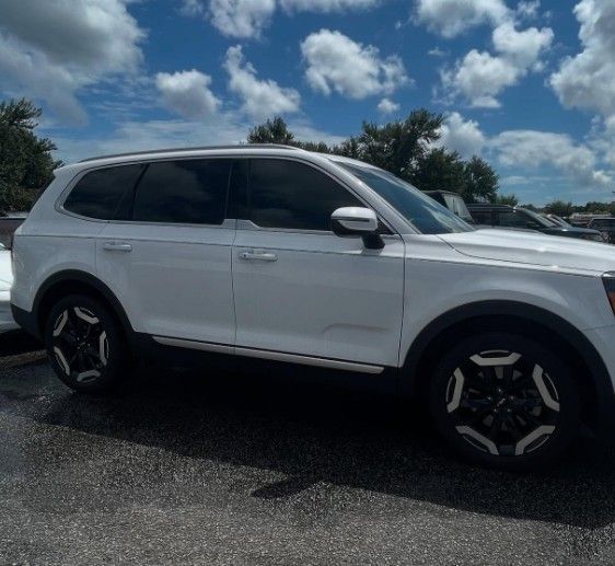White Kia Telluride SUV parked outside on a sunny day.