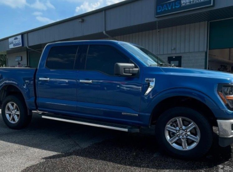 Blue Ford pickup truck parked in front of a building with a “Davis Detail” sign.