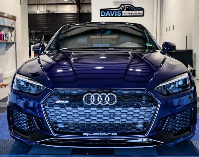 Dark blue Audi RS5 with a black grille in a shop.