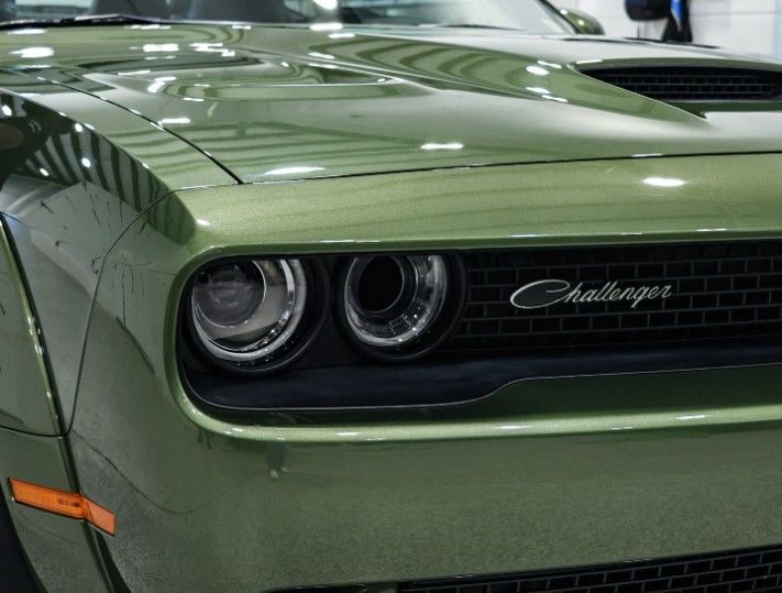 Green Dodge Challenger car front view, with a black grille and headlights.