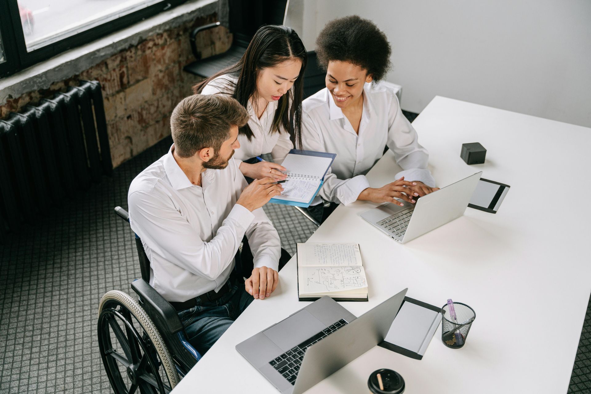 A man in a wheelchair is sitting at a table with two other people.