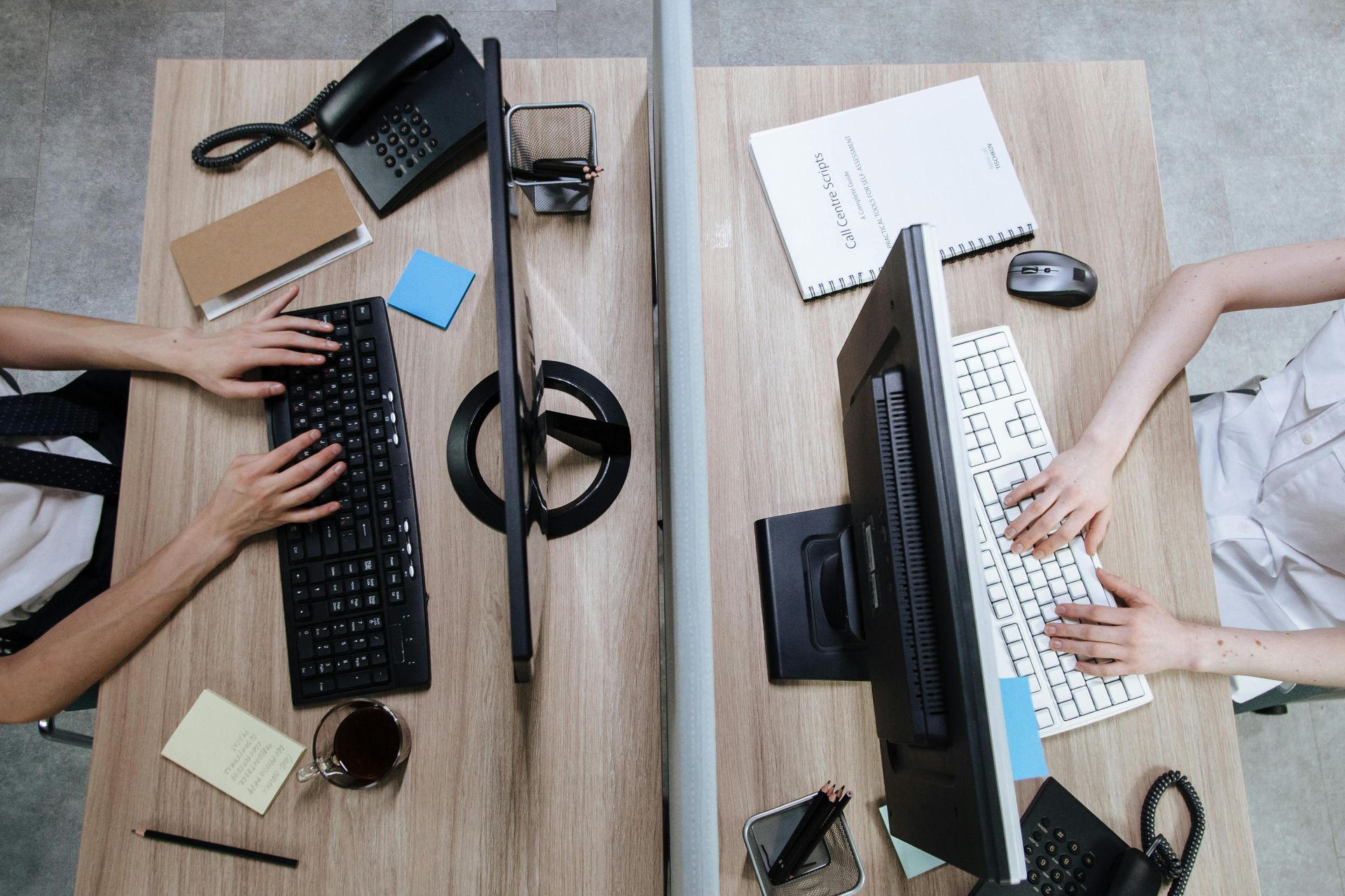Two people are sitting at a desk using computers.