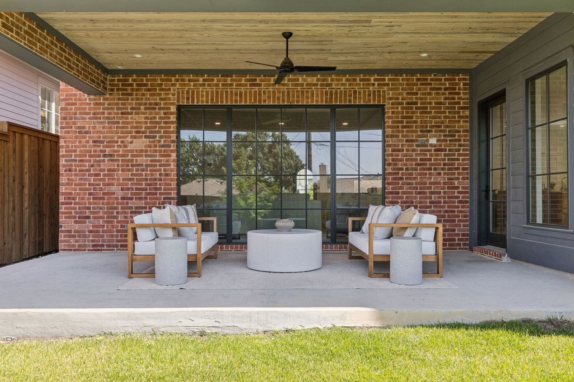Covered patio with brick wall, seating, and a large window.