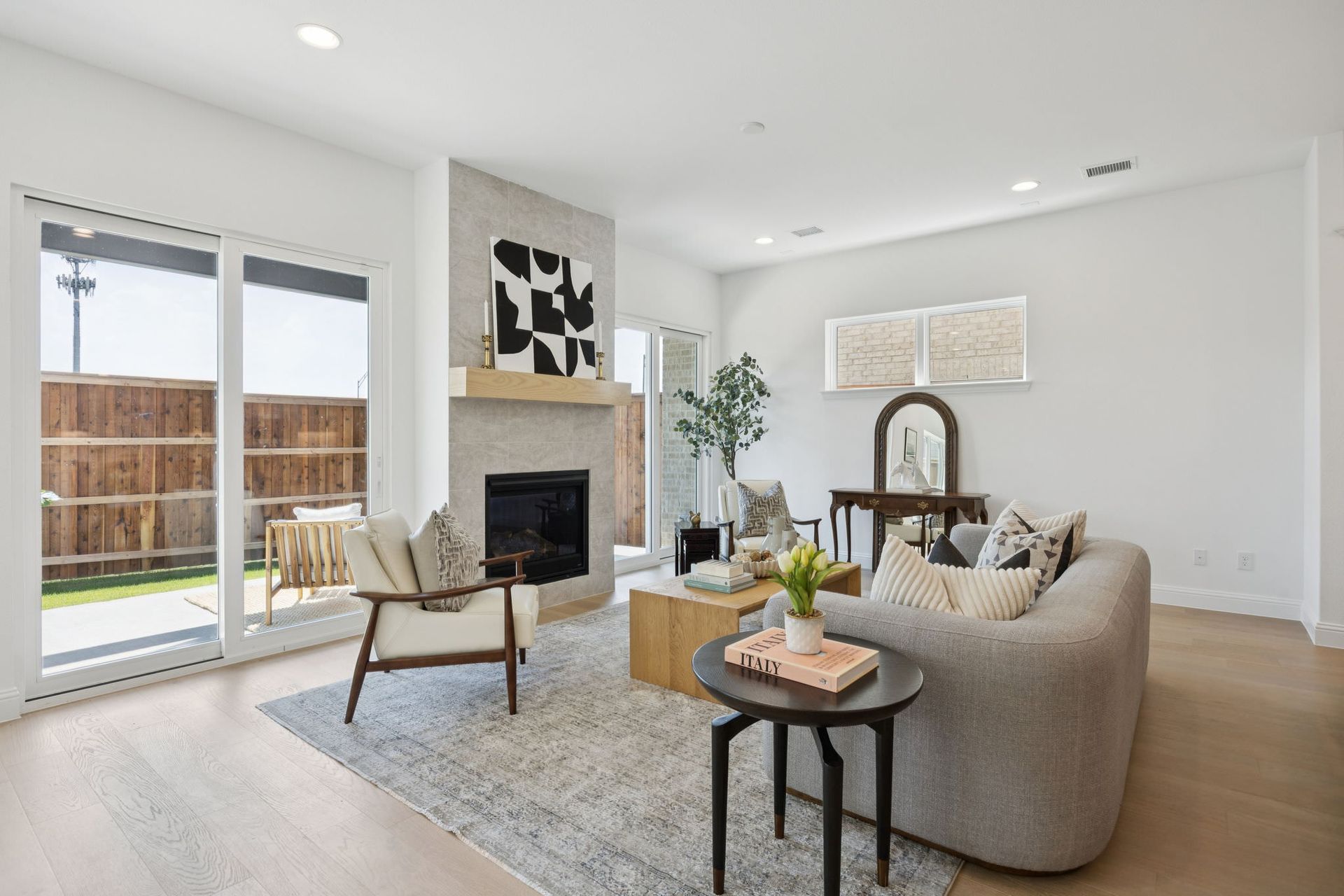 Modern living room with fireplace, sliding glass doors, neutral color palette, and wooden floors.