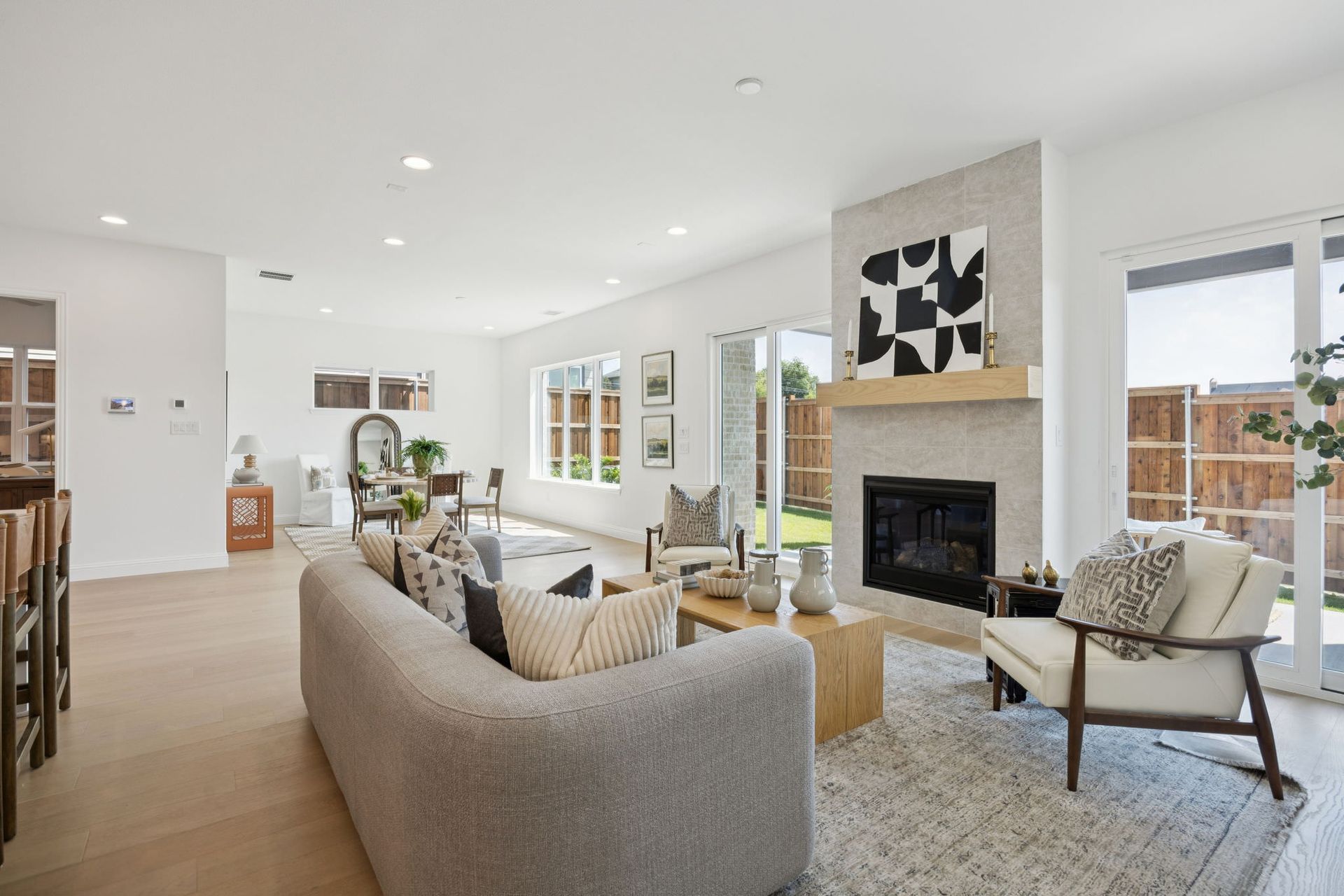 Living room with fireplace, sofa, chairs, and large windows with outdoor view.