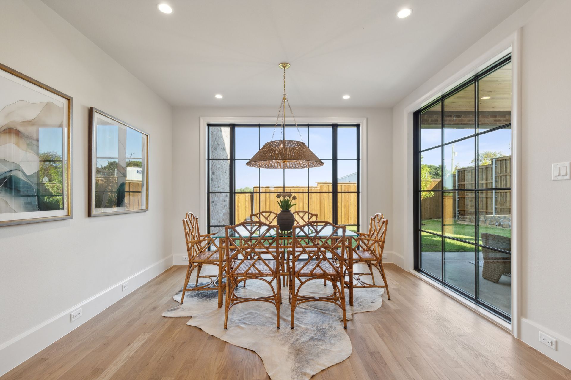 Dining room with table, chairs, large windows, cowhide rug, and art.