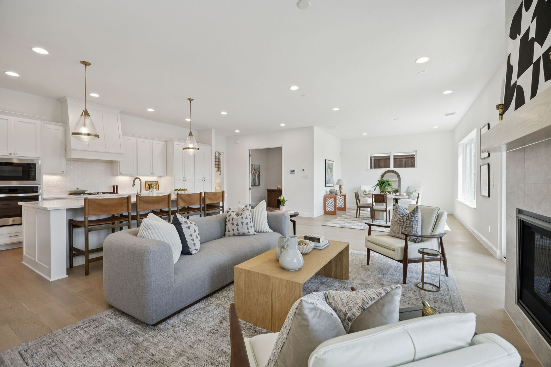 Open-concept living space with a kitchen, dining area, and living room. Neutral colors and modern furniture.