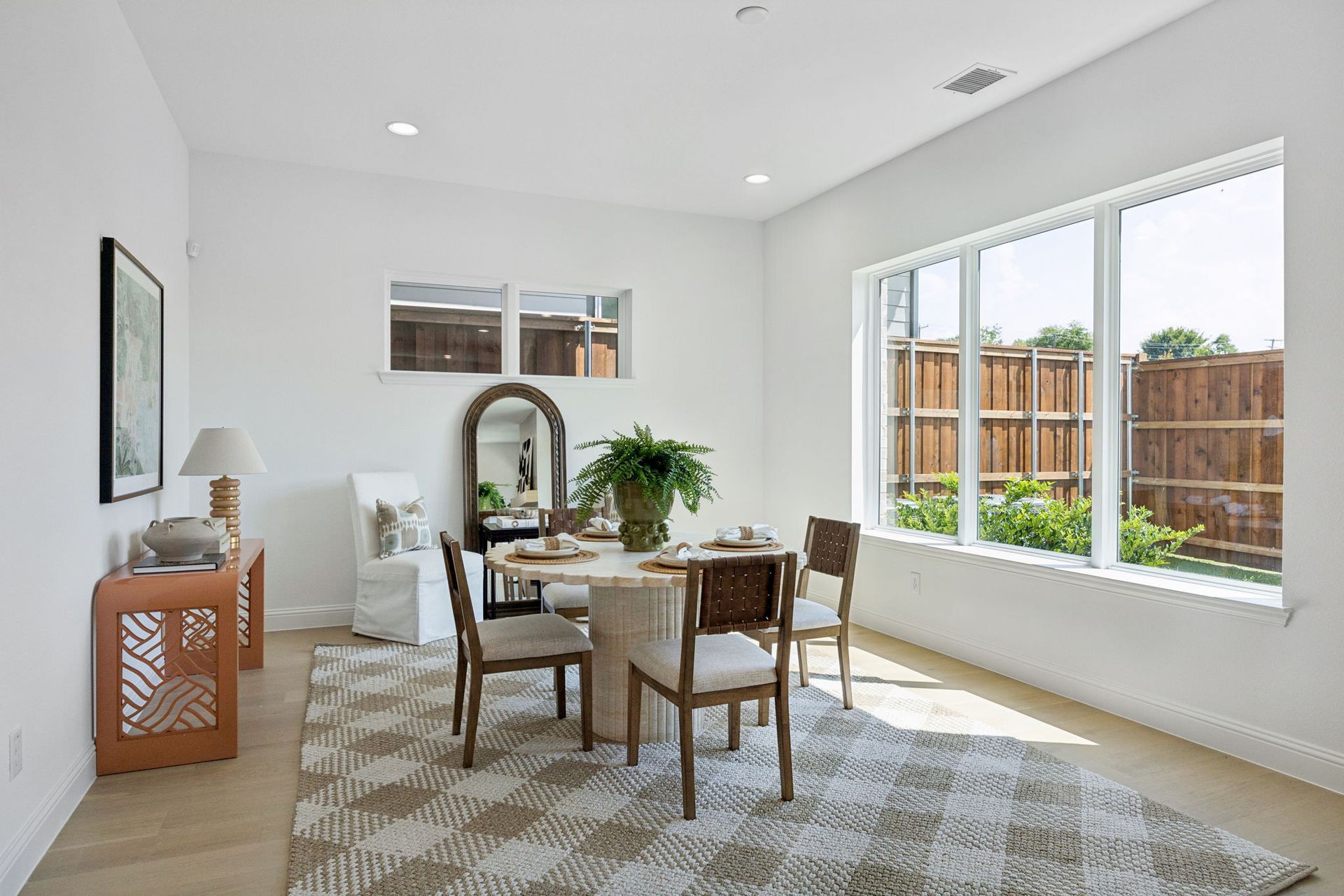 Dining room with round table, four chairs, large windows, rug, and decorative items.