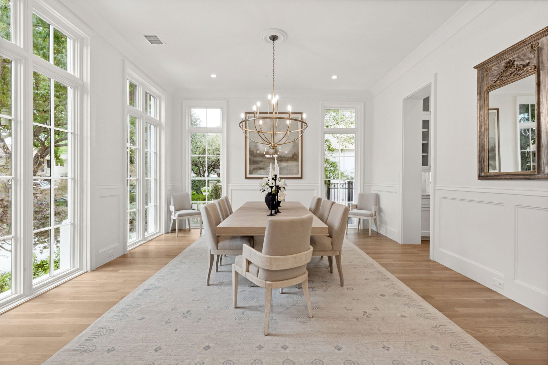 A dining room with a long table and chairs and a mirror.