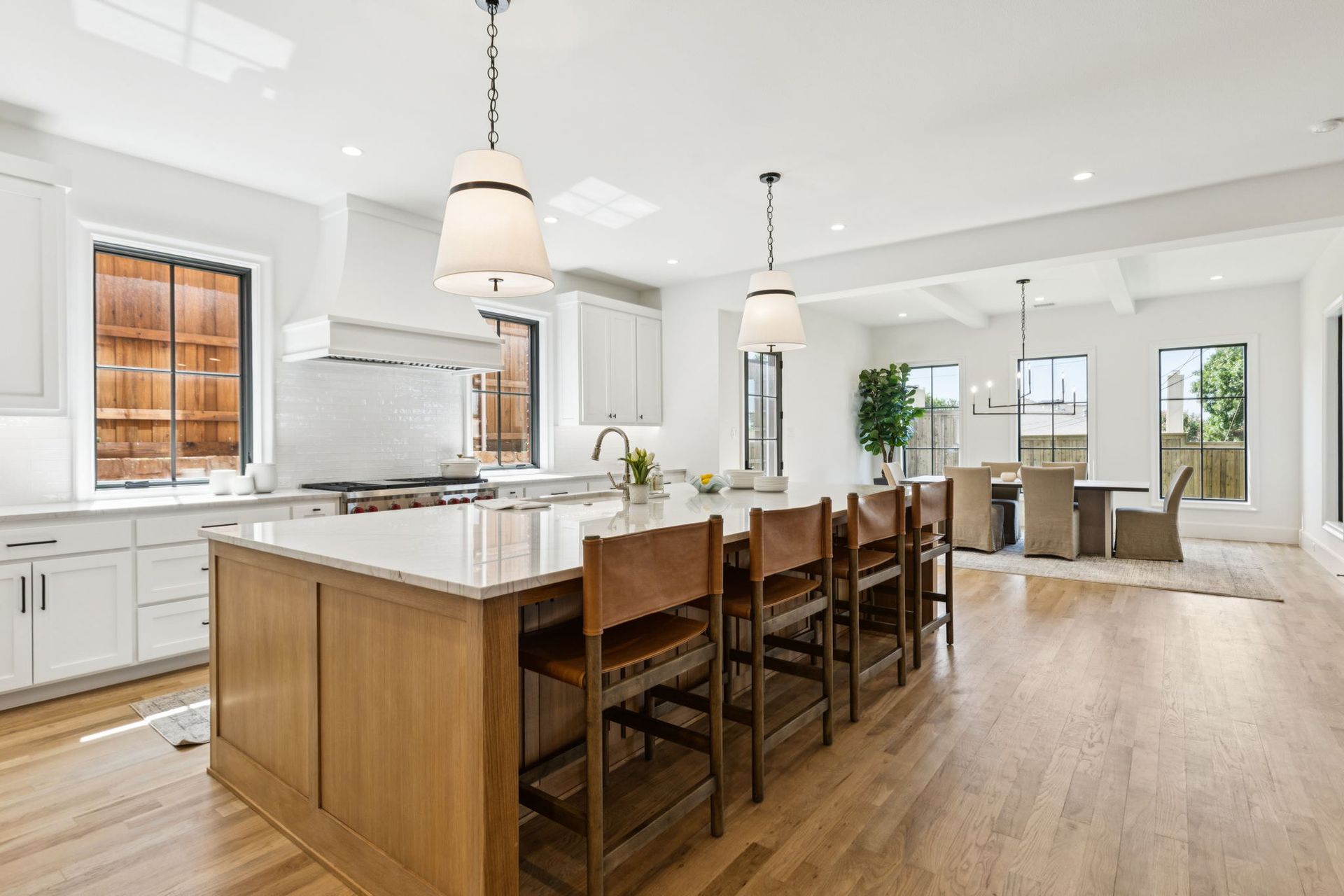Spacious kitchen with a large island and seating, white cabinetry, and wooden floors.