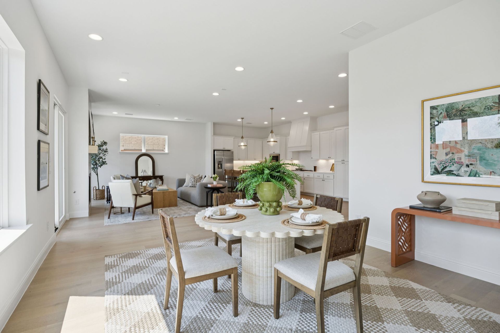 Spacious, bright dining area with round table, chairs, and open view into living room and kitchen.