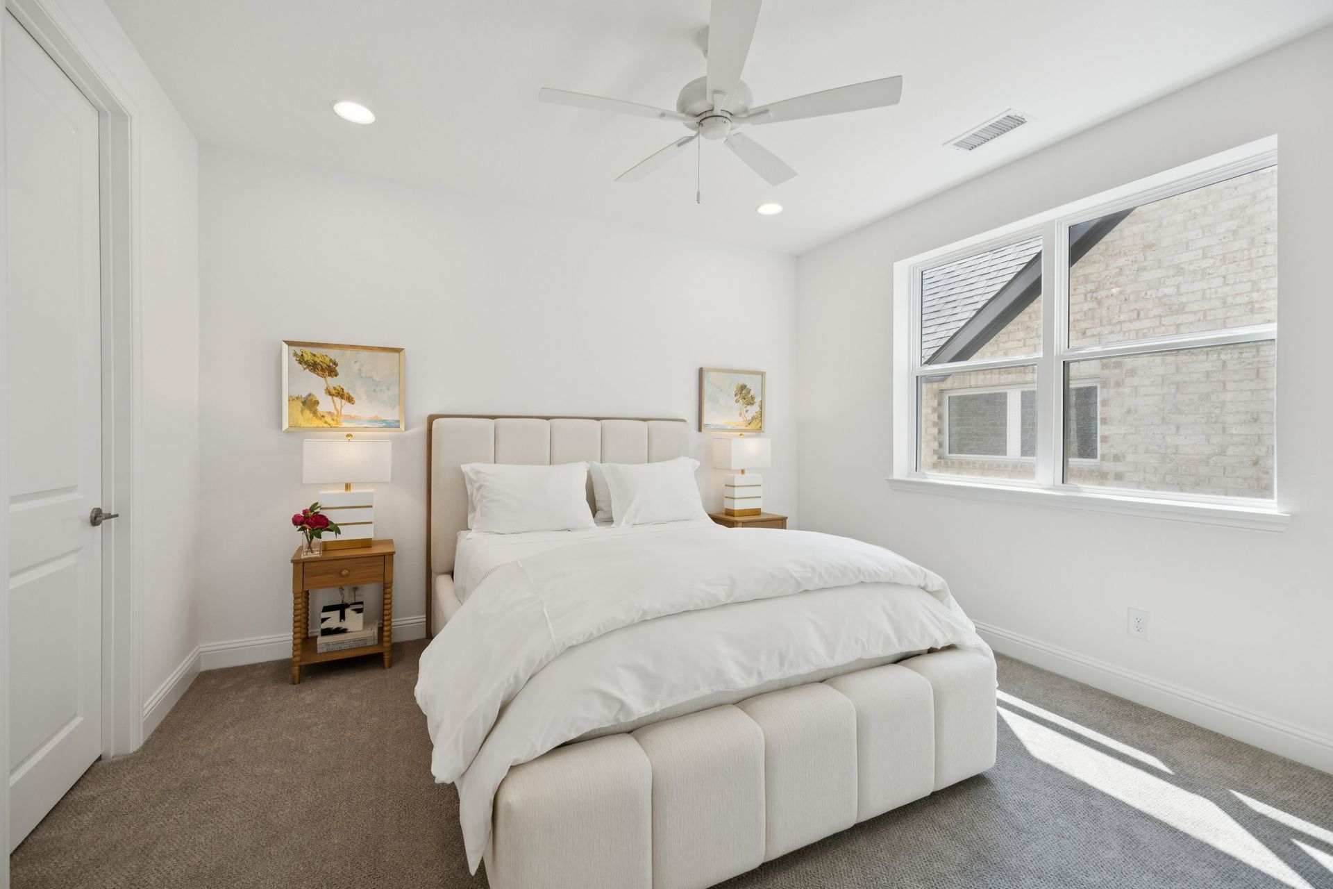 White bedroom with a bed, nightstands, and window; neutral tones.