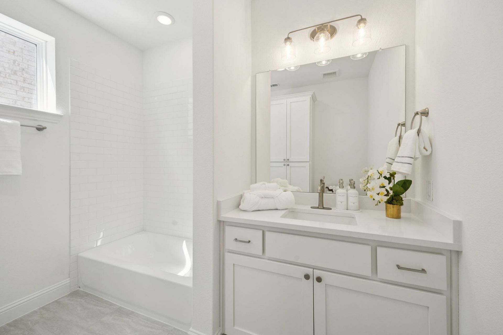 White bathroom with vanity, mirror, and shower/tub combo.
