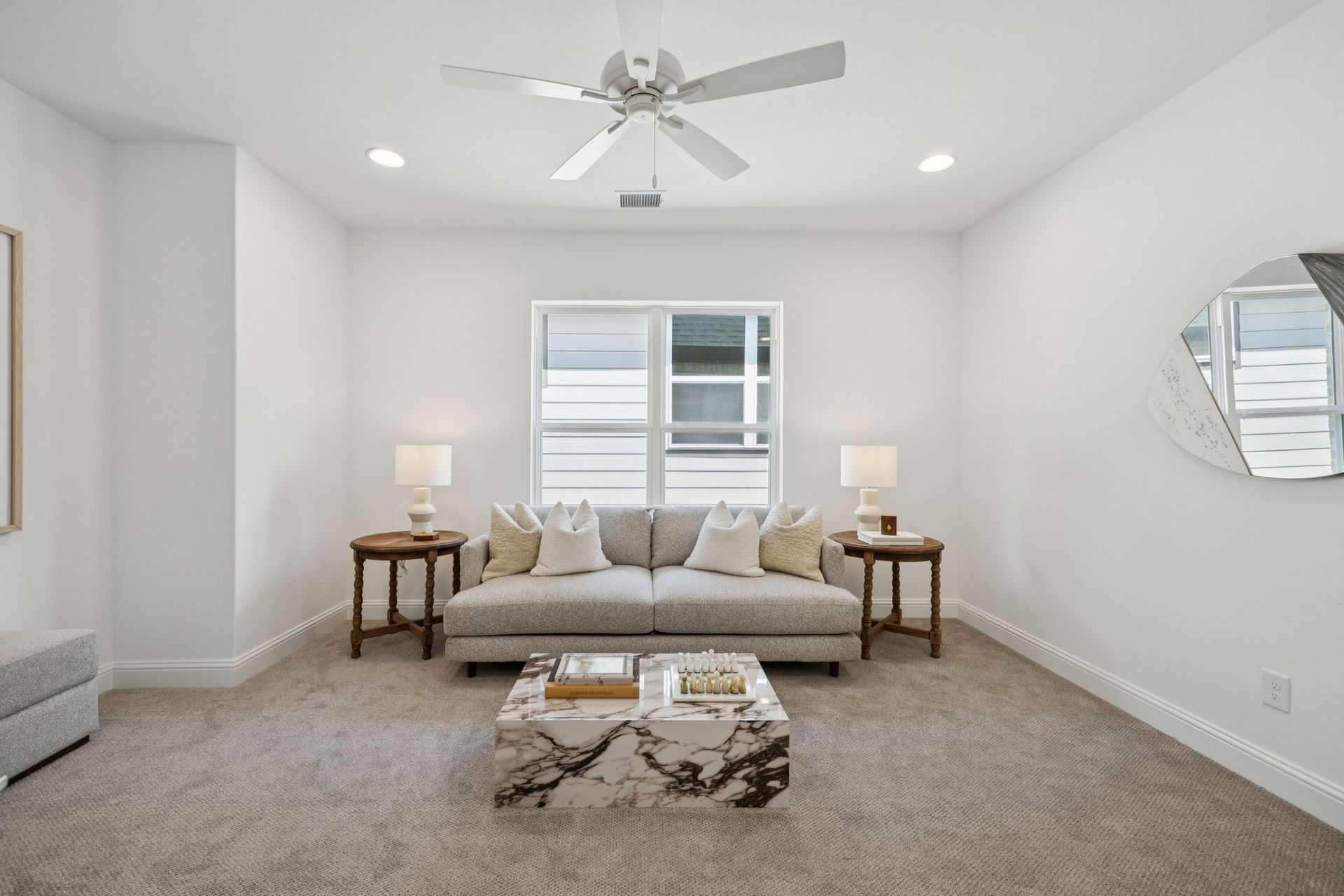 Living room with sofa, coffee table, lamps, and a window.