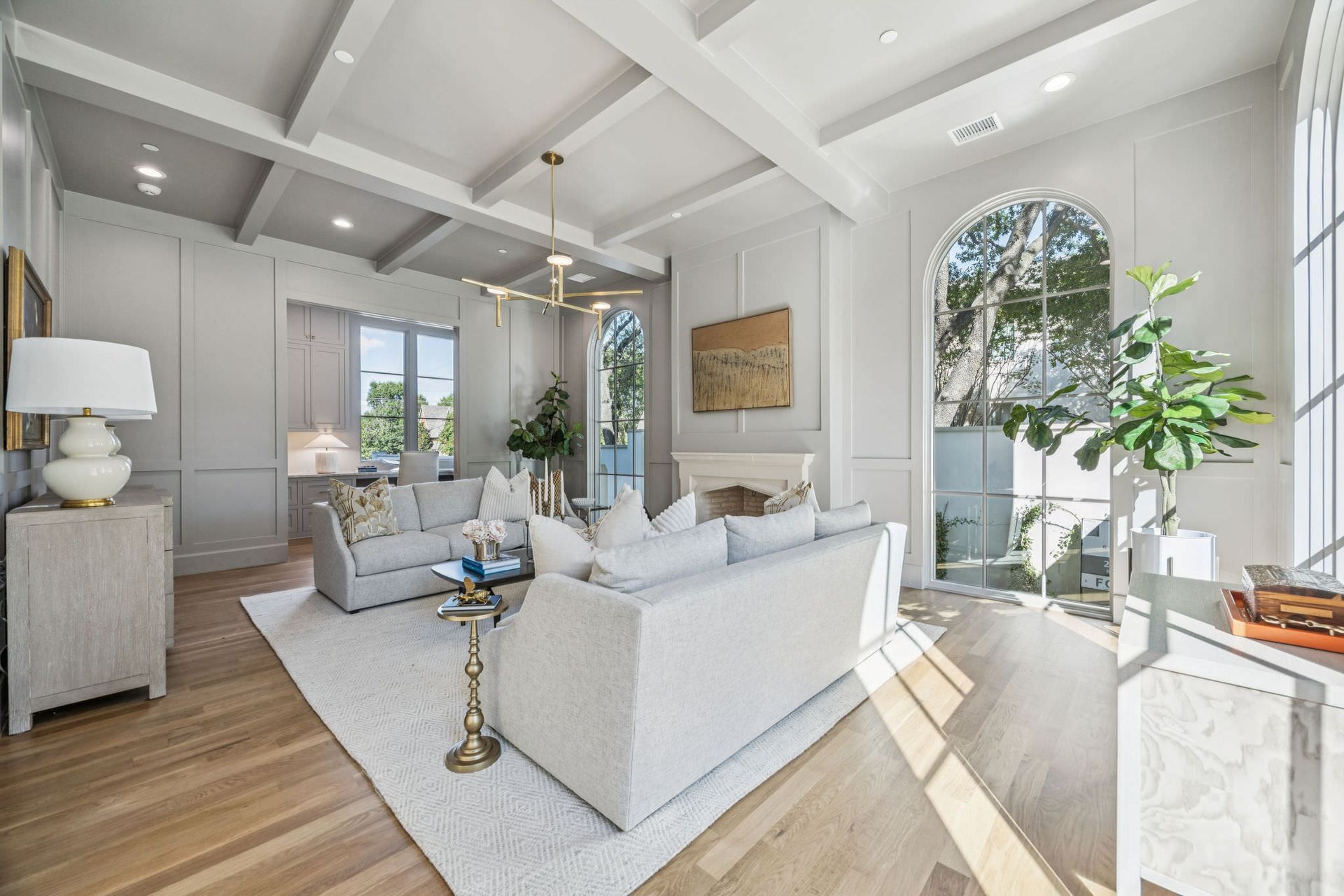 Bright living room with white sofas, large windows, and hardwood floors.