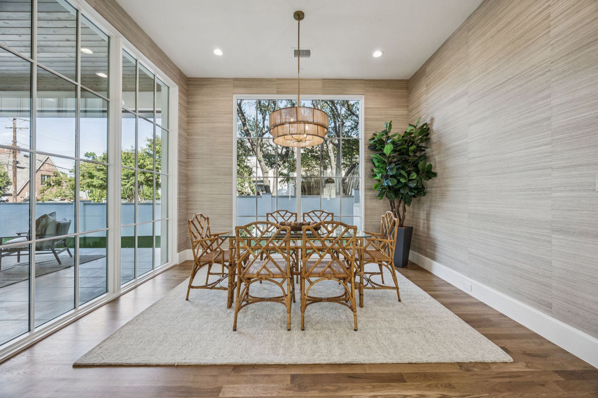 Dining room with large window, table, chairs, neutral-toned walls, and rug.