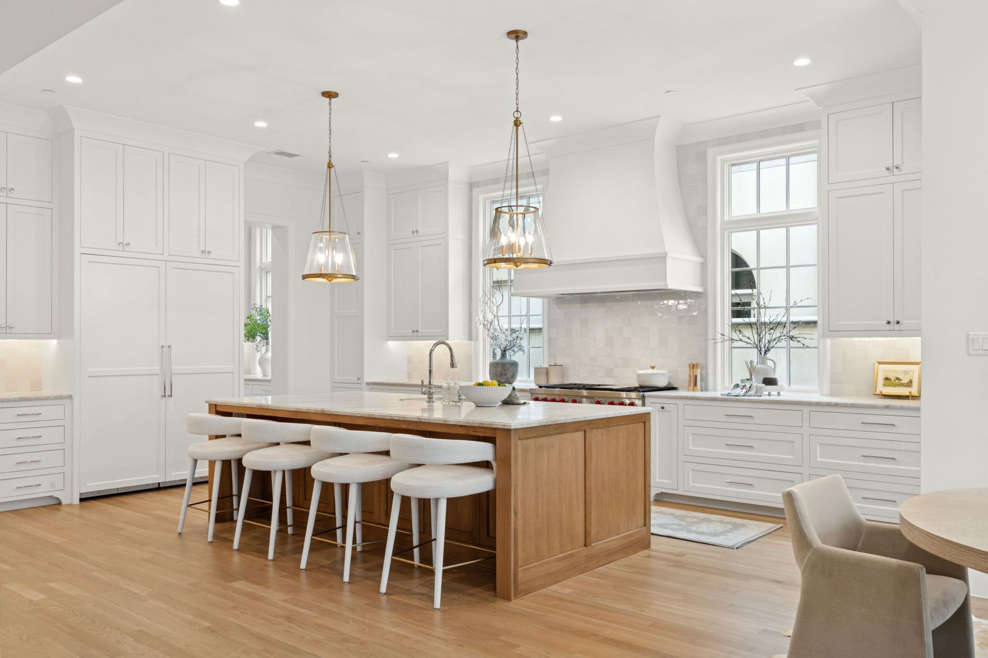 Bright white kitchen with wooden island, pendant lights, and bar stools.