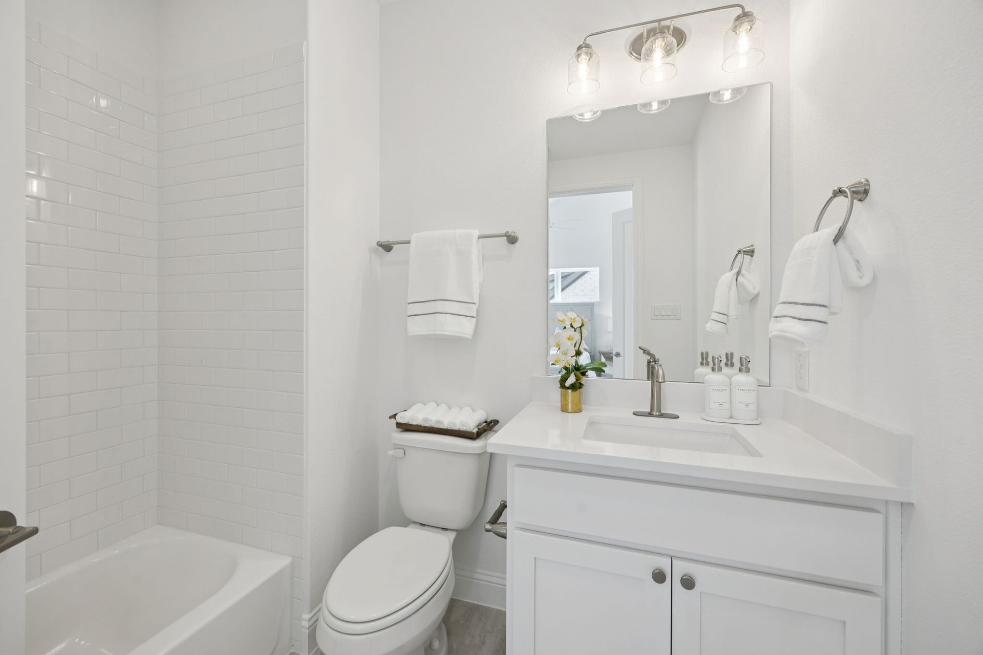 White bathroom with a tub, toilet, vanity, and mirror, all in white.