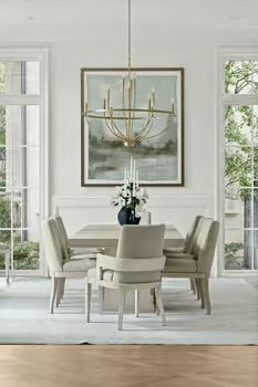 Dining room with table, chairs, art, chandelier, and windows. Soft color palette, elegant setting.