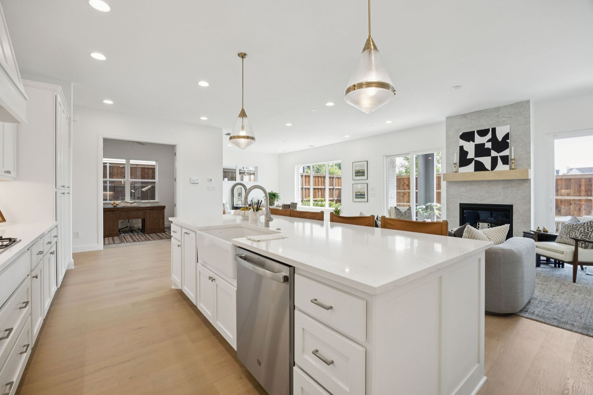 Open-concept kitchen and living room with white cabinets, large island, and fireplace.
