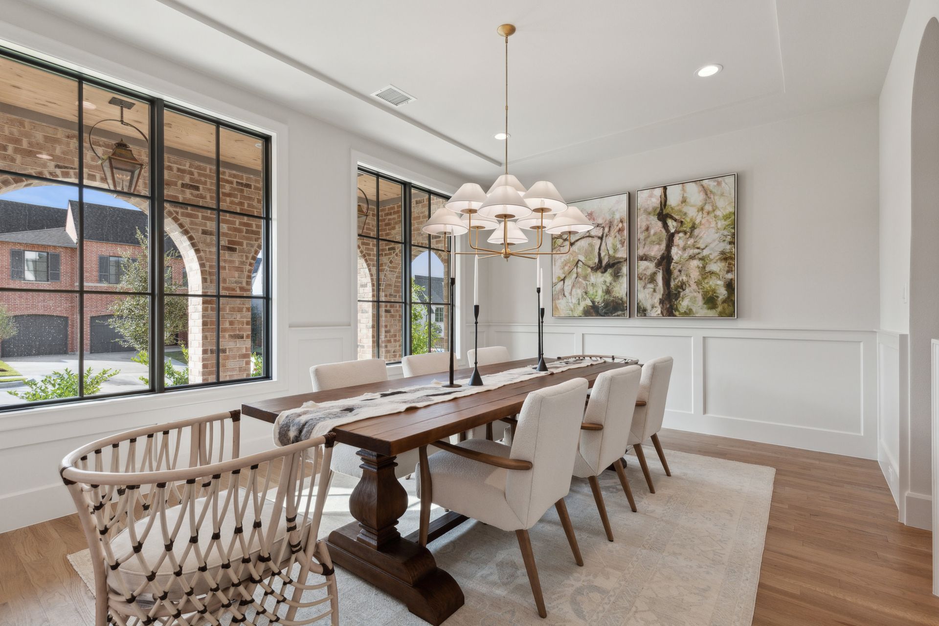 Elegant dining room with large windows, long wooden table, and chairs.
