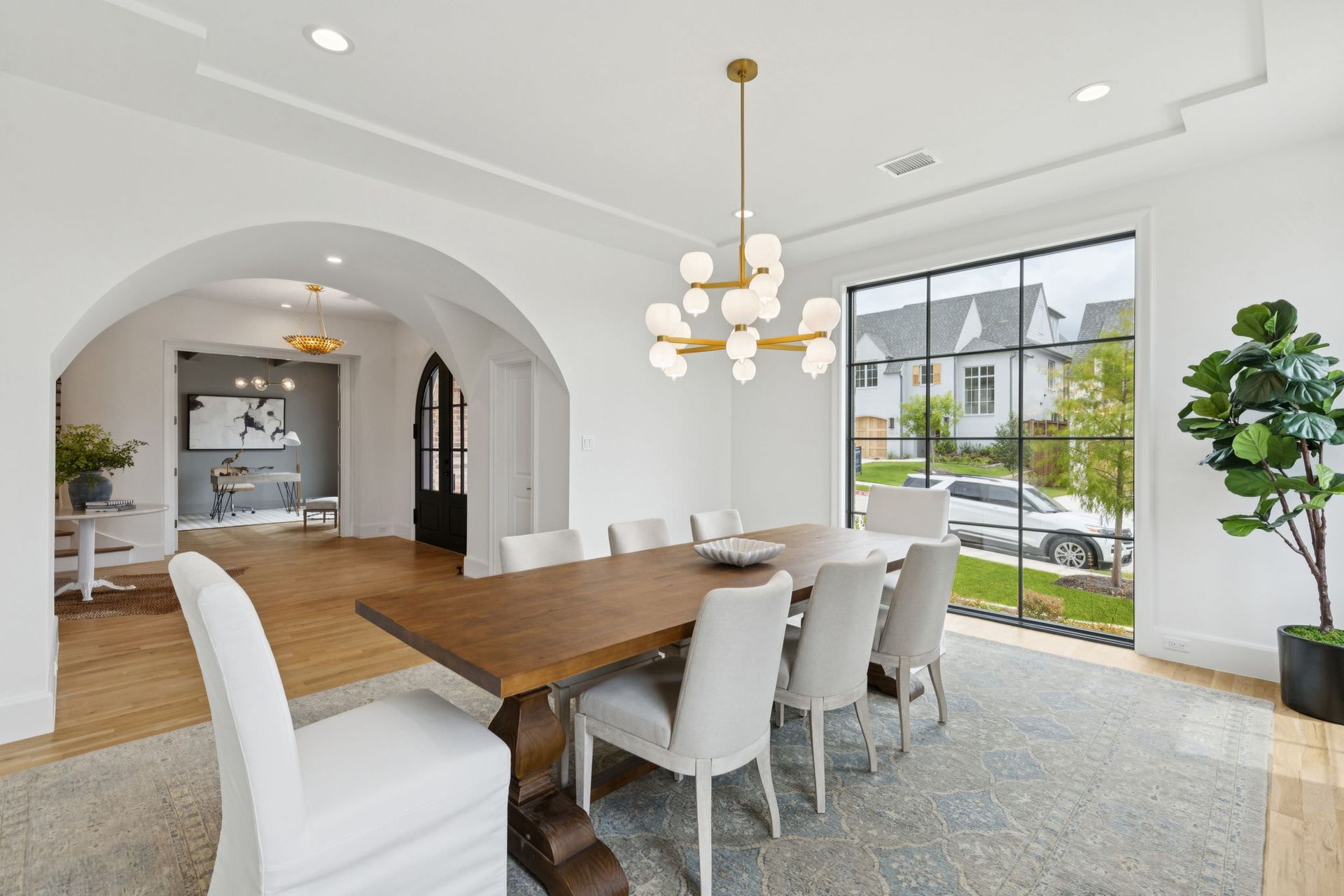 Spacious dining room with wooden table, light chairs, and large window overlooking a street.
