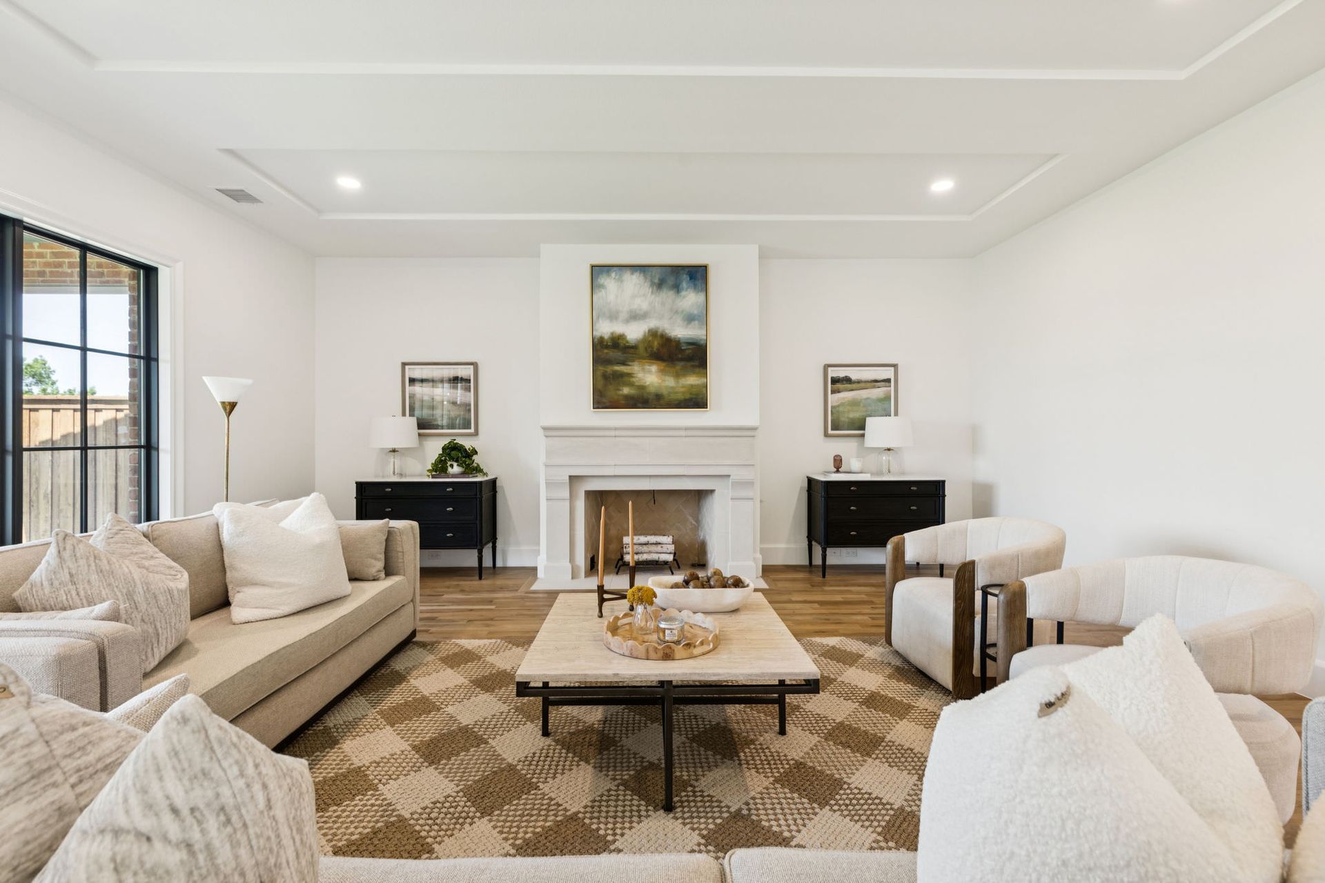 Living room with light-colored sofa, chairs, fireplace, artwork, and patterned rug.