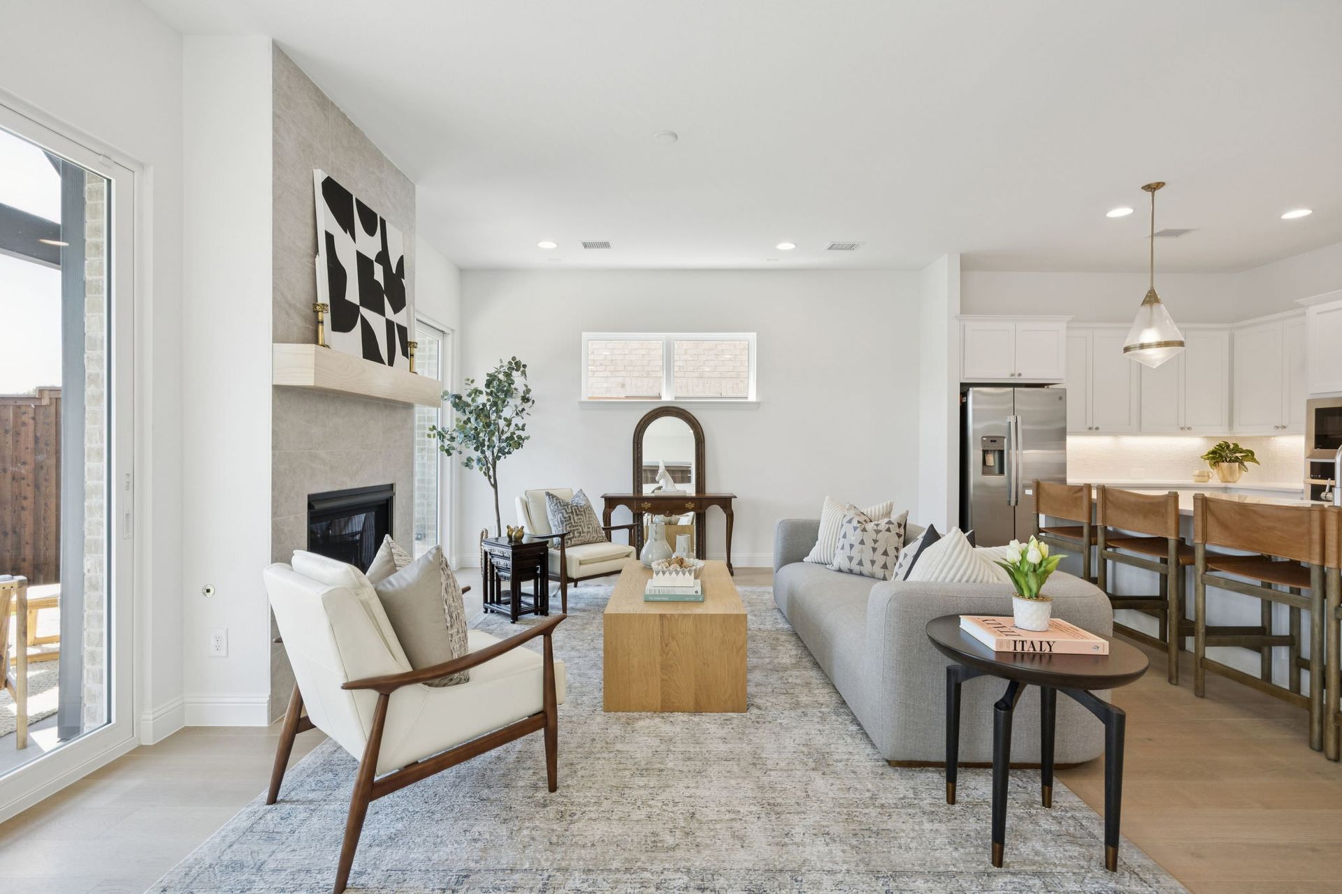 Bright, modern living room with fireplace, white walls, and open-plan kitchen.