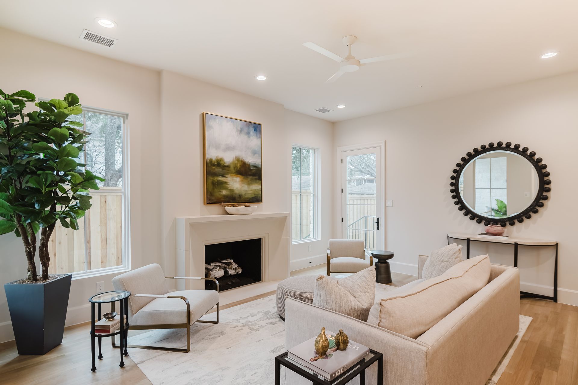 A living room with a couch , chairs , a fireplace and a mirror.