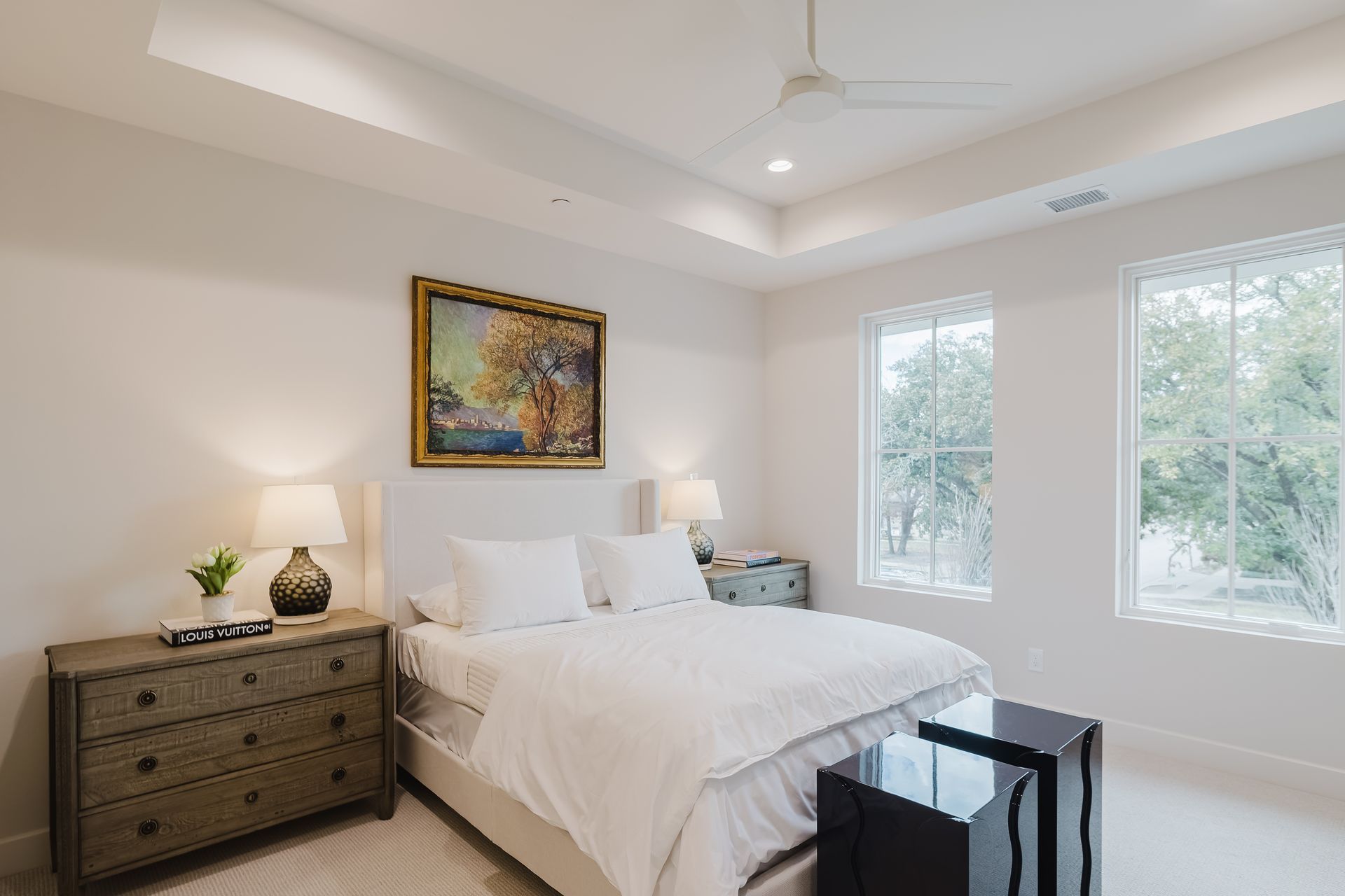 Bedroom with white bedding, two windows, two nightstands, and a painting.