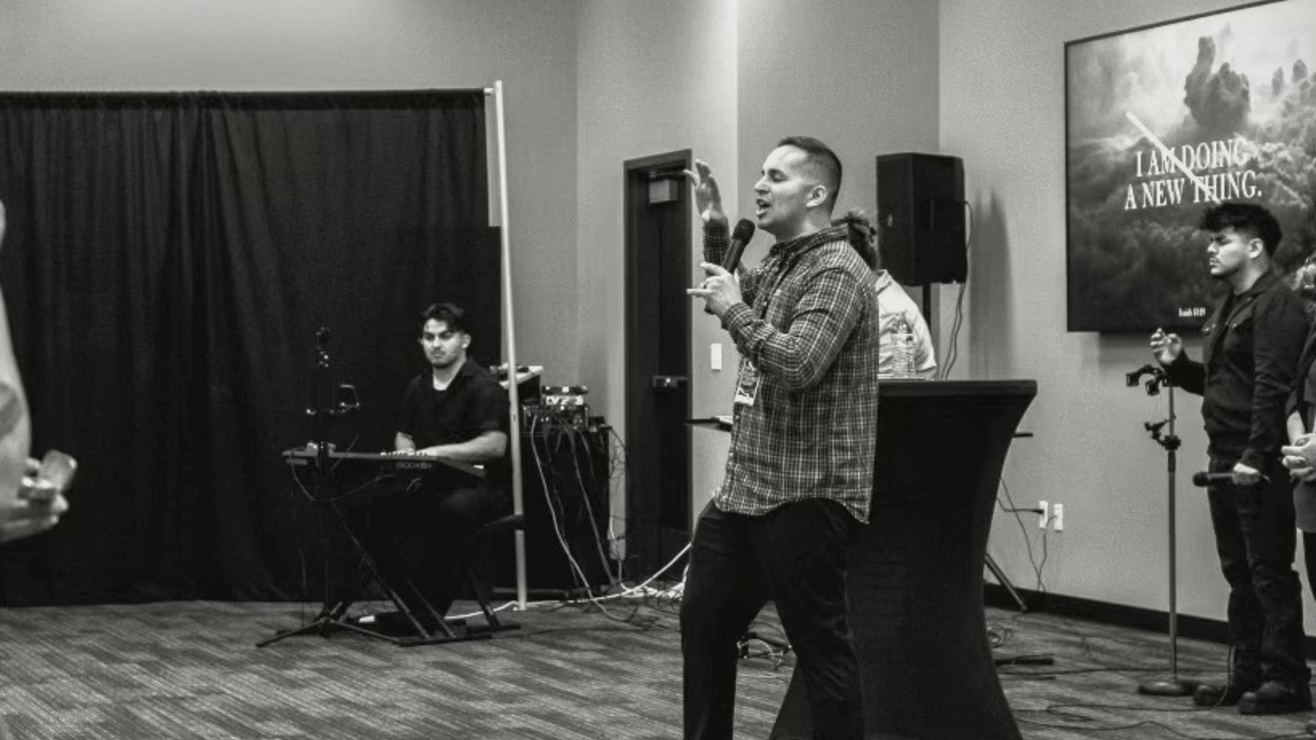 A man is standing in front of a microphone in a room.