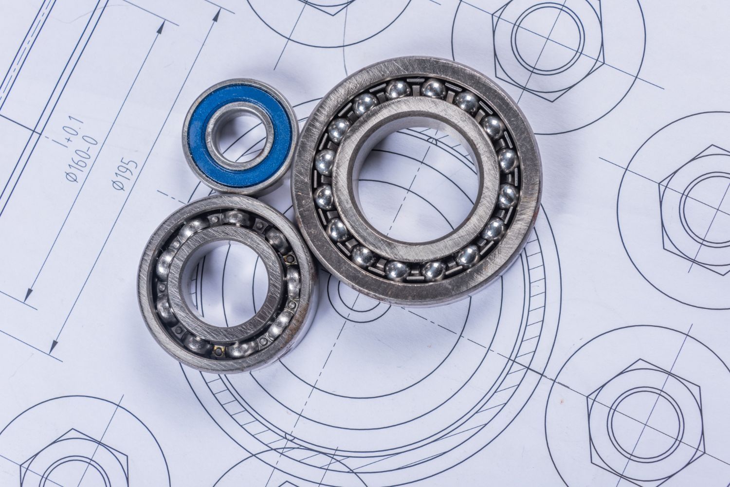 Tre cuscinetti a sfera metallici su un disegno tecnico
