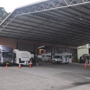 A row of rvs are parked under a covered area.