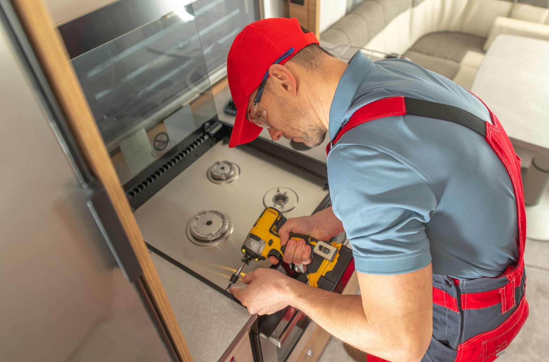 A man is working on a gas stove in a kitchen.