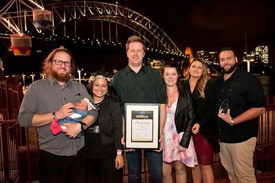 A group of people standing next to each other holding a certificate in front of a bridge.