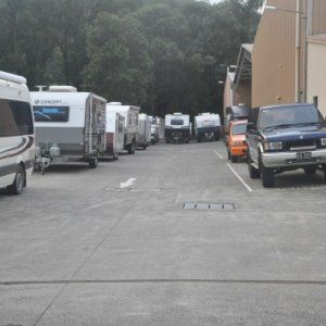 A row of rvs are parked in a parking lot next to a building.
